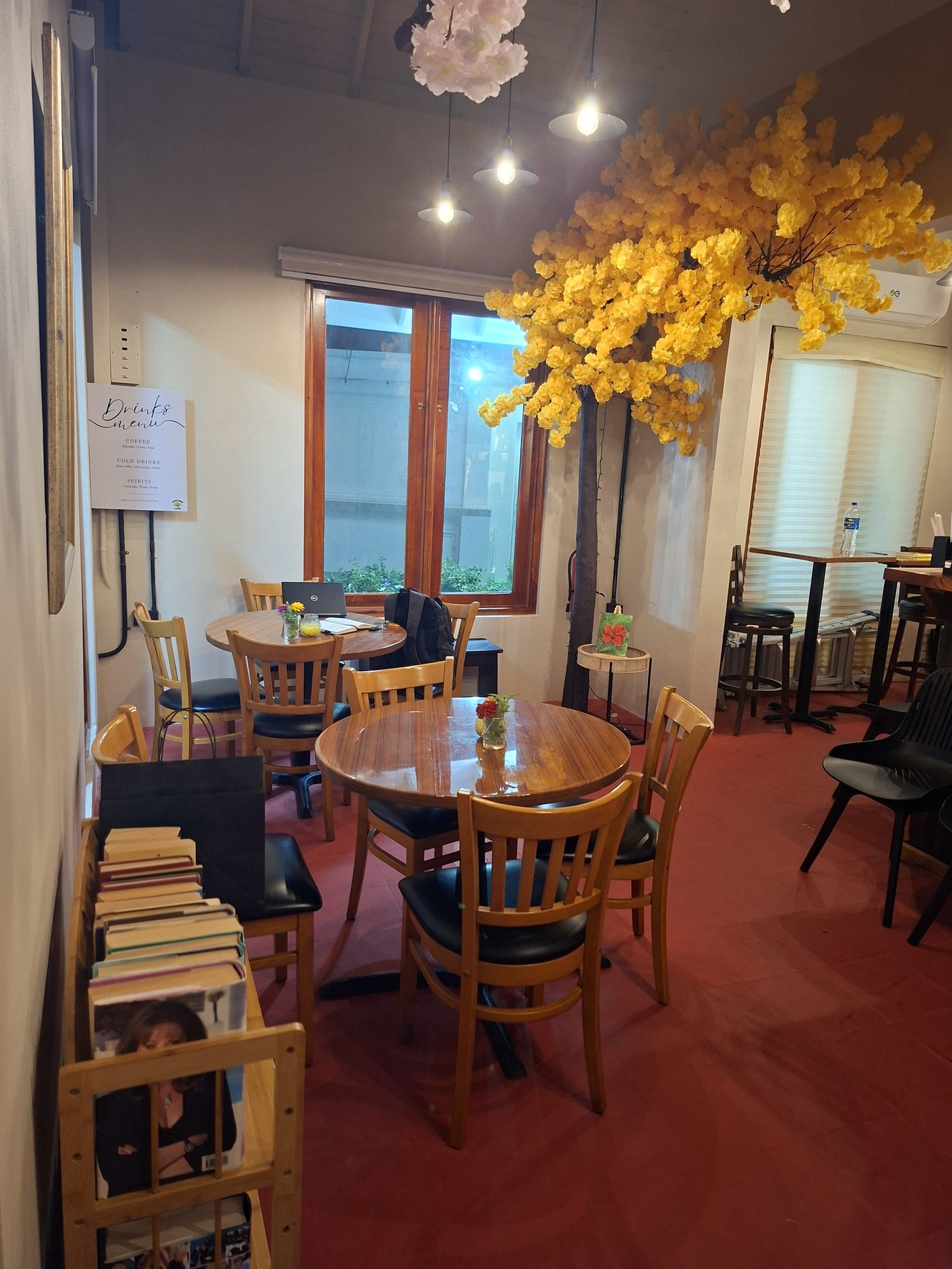The book nook corner inside Poui Tree Café, beneath the yellow blossom tree feature